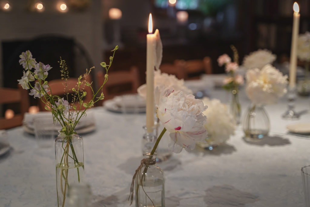 Table decorations of a lit candle and peony's at Palma NYC restaurant.