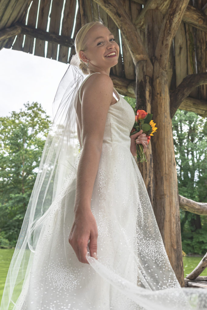 POV looking up wedding portrait of Kat Gaffney under the pavilion of Wagner Cove.