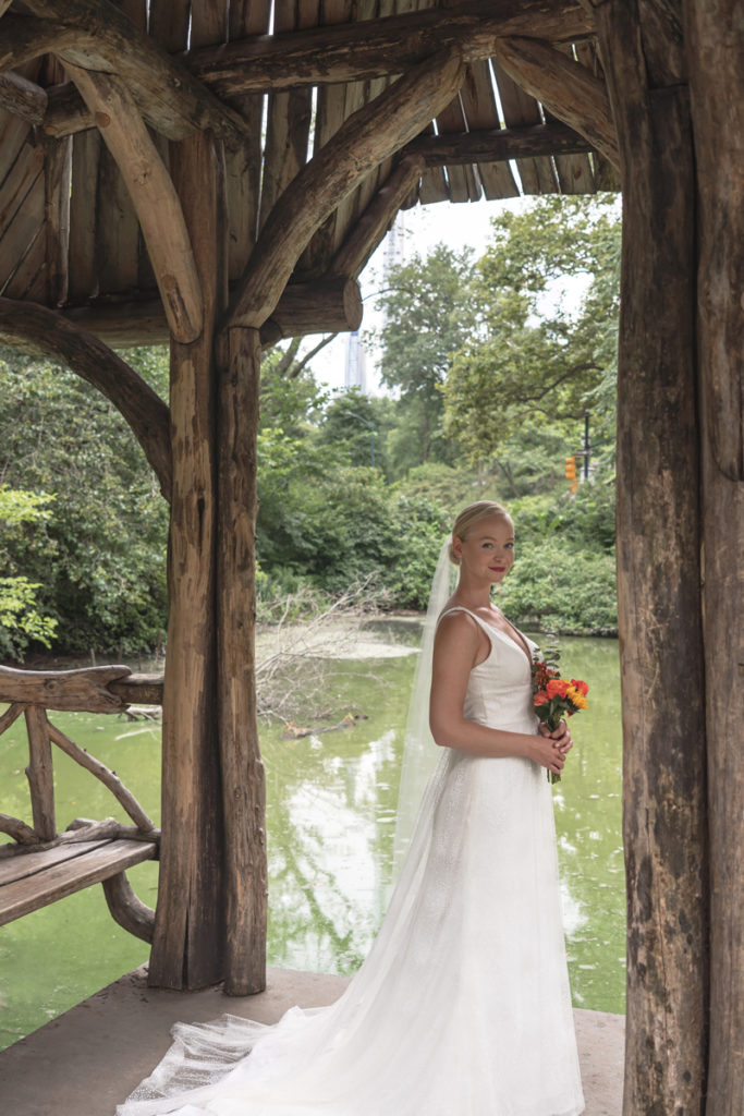 Full body wedding portrait of Kat Gaffney under the pavilion of Wagner Cove.