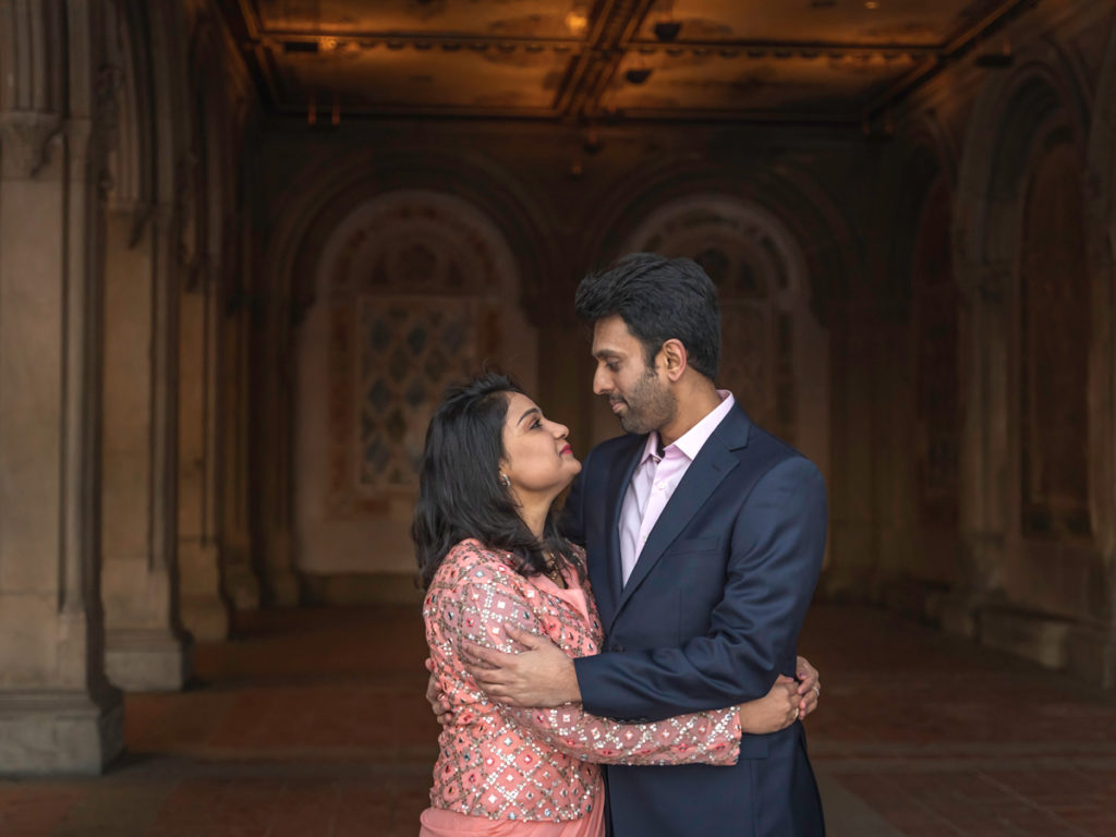 An Indian couple embraces and looks at each other lovingly inside Bethesda Terrace and fountain in Central Park.