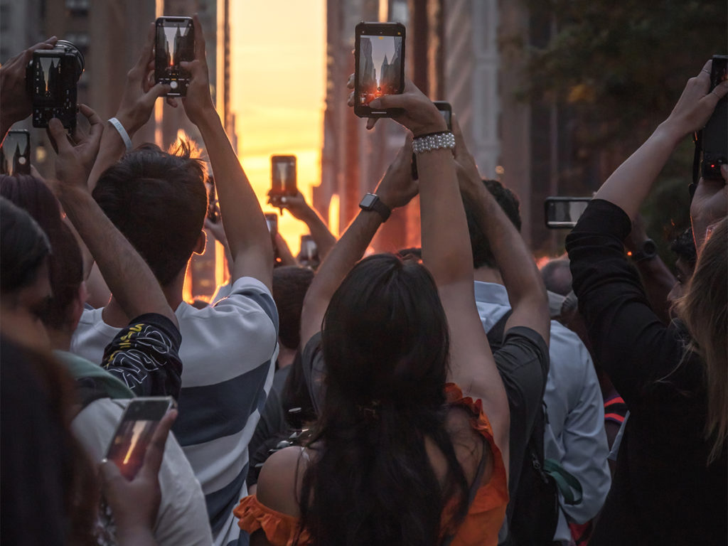 Picture of pedestrians taking pictures of Manhattanhenge with their phone at Tudor City.