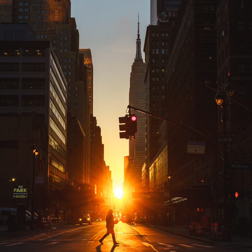 Silhouette of a pedestrian walking in front of Reverse Manhattanhenge on 34th Street.