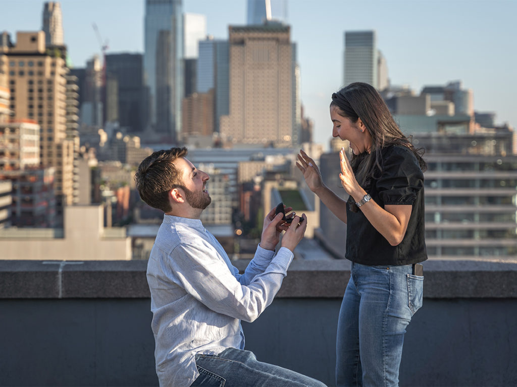 Candid moment of Jordan Zauderer and his fiancé during their West Village rooftop engagement.