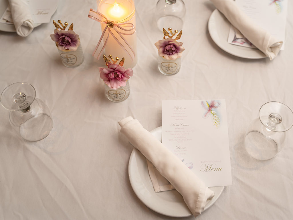 Dinner table settings at a baby's baptism reception.