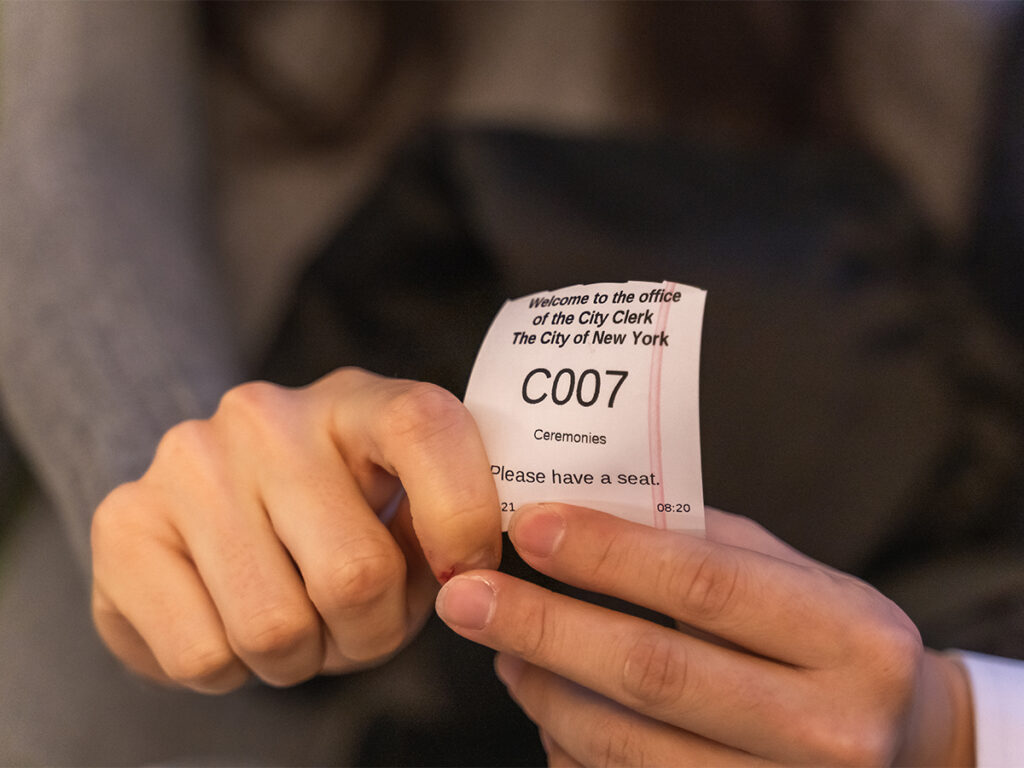 Couple holds a ticket for their spot to get married at NYC City Hall.