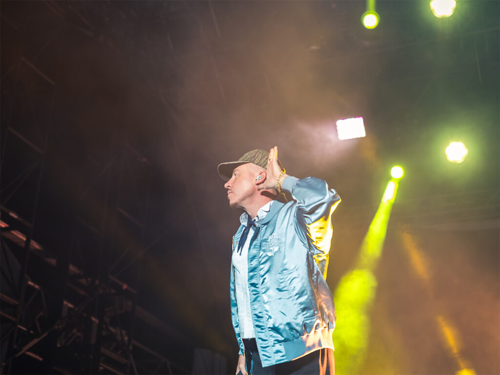 Rapper Macklemore puts his hand to his ear listening to the audience sing along to his songs at The Rooftop at Pier 17.