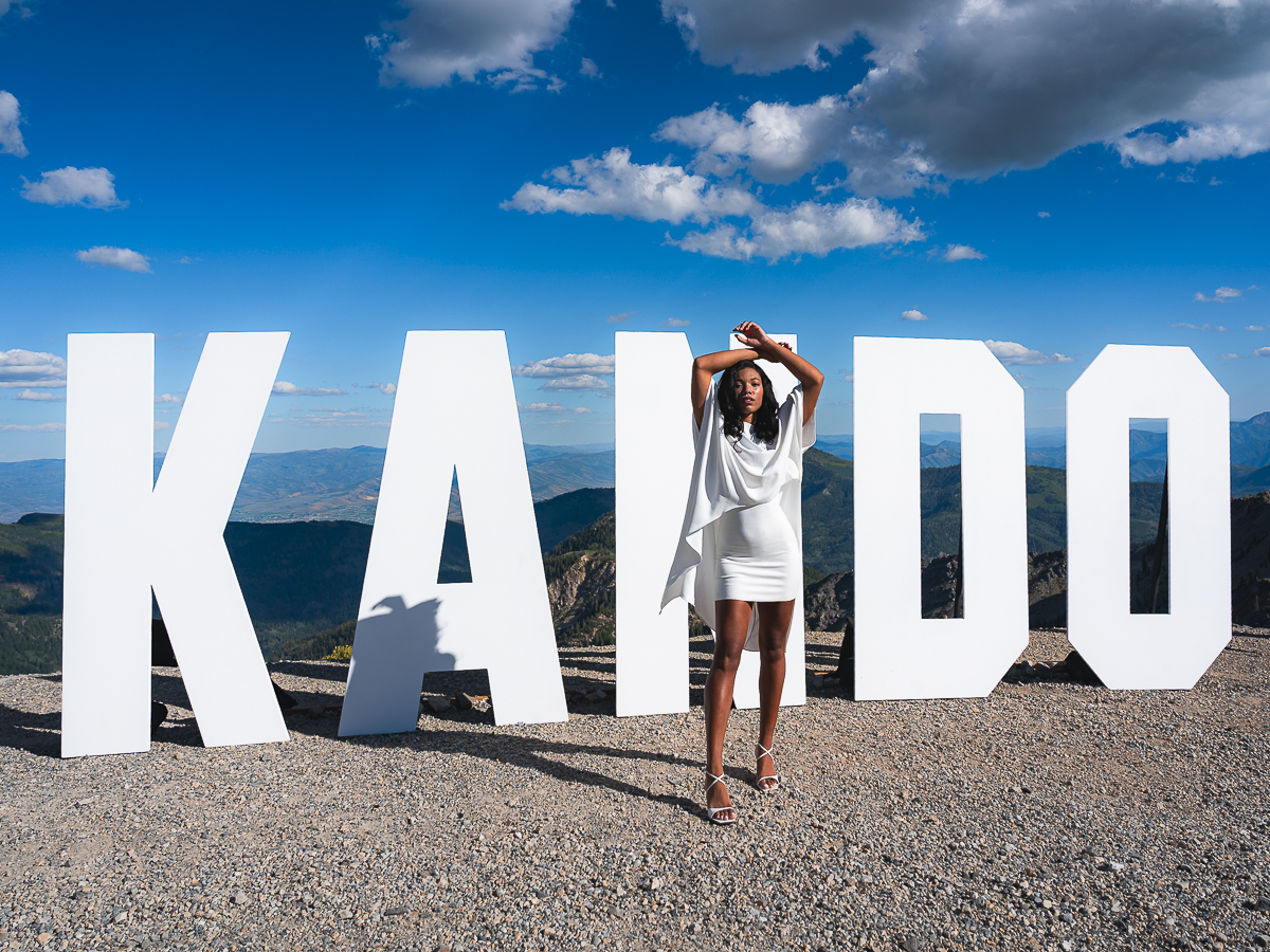 Model poses at the Sony Kando Trip sign atop Snowbird's summit in Utah.