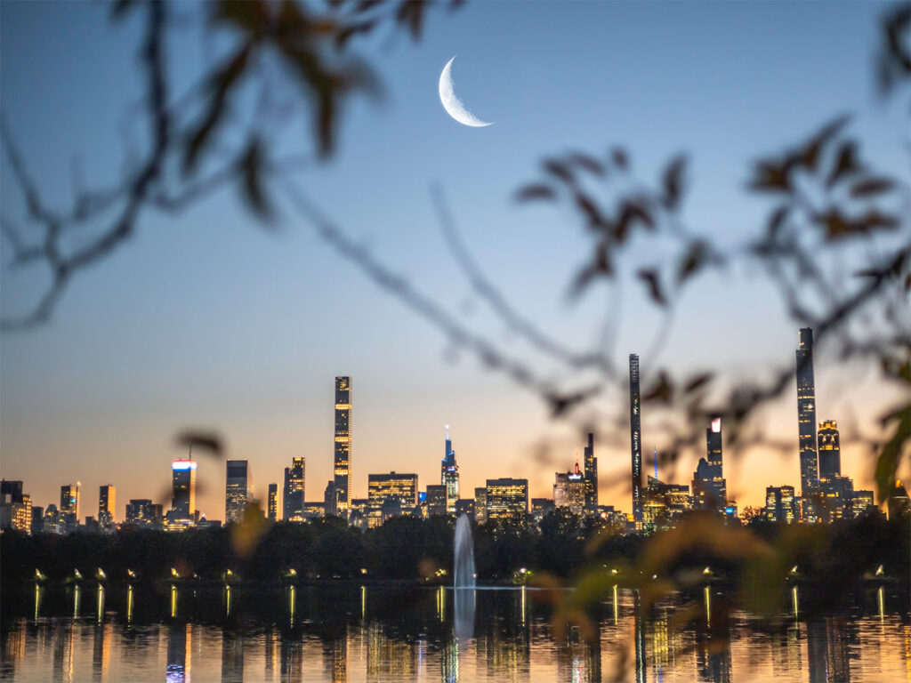 A crescent moon rises above Billionaire's Row in Central Park.