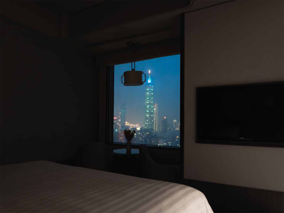 Night view of the Horizon Deluxe Room with the the glittering Taipei 101 skyline outside the window.