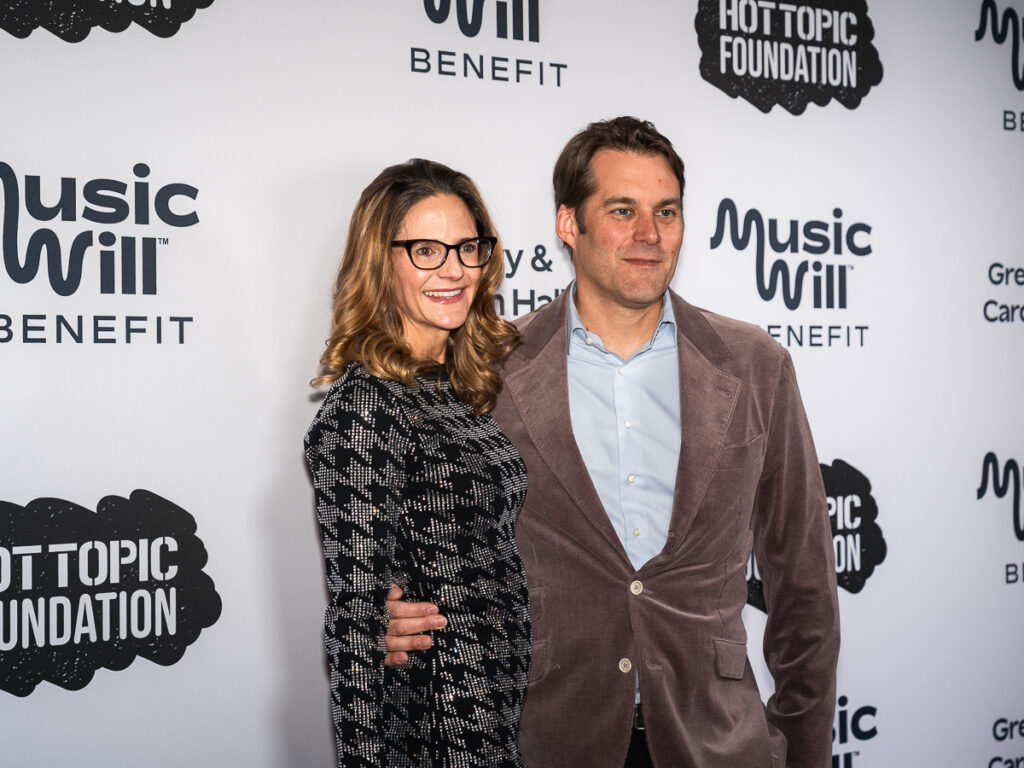 Gregory Hall, Music Will Benefit Co-Chair + Presenting Sponsor and his wife take pictures on the Music Will 2025 Benefit Red Carpet.