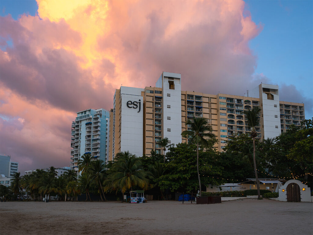 Exterior of Fairmont El San Juan with a pink sunset.