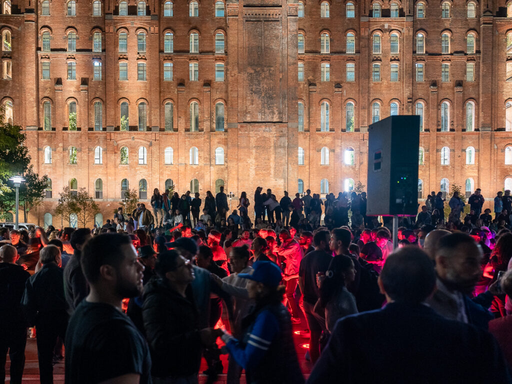 A crowd salsa dances the night away in front of the Domino Park Sugar Factory.