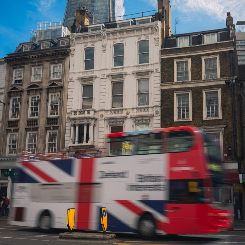 The iconic double decker bus in London whizzes by the street.