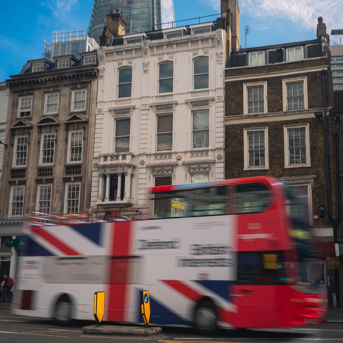 The iconic double decker bus in London whizzes by the street.
