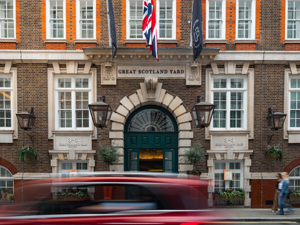 Exterior of the Great Scotland Yard Hotel with a slow shutter capture of a car passing in front.