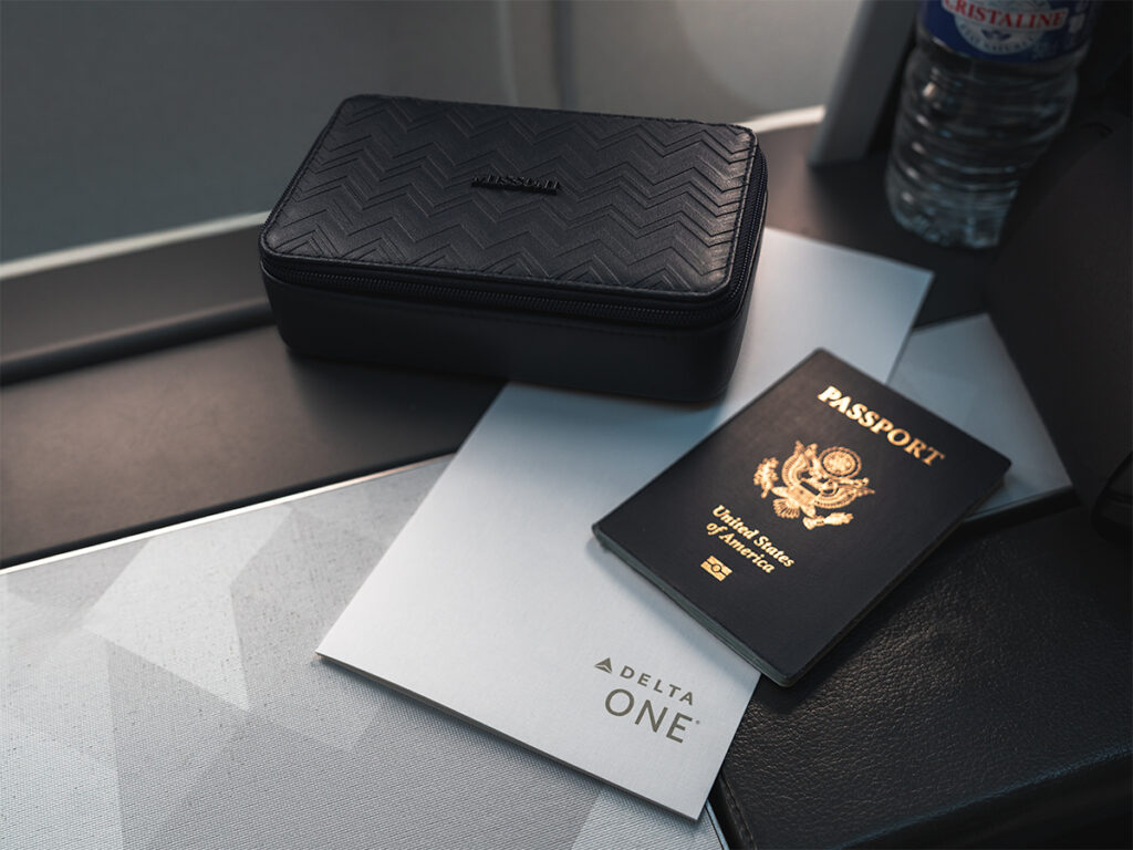 Detail shot of Delta One Business Class meal menu, USA passport, and Missoni amenity kit.