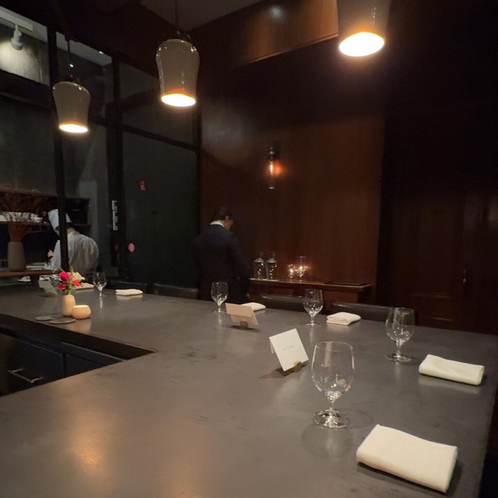 Chef's counter seating wrapped around the open kitchen at Atera NYC, a two Michelin star restaurant in Tribeca