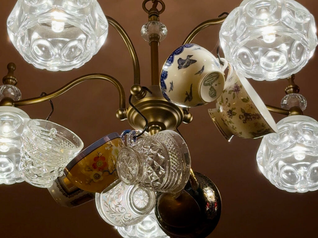 Antique chandelier decorated with hanging mismatched teacups at The Parlour, part of Brooklyn High Low's aesthetic.