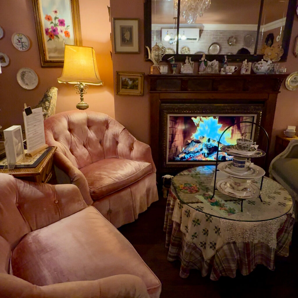 Cozy pink velvet armchairs beside a fireplace inside The Parlour, Brooklyn High Low's Park Slope tea room