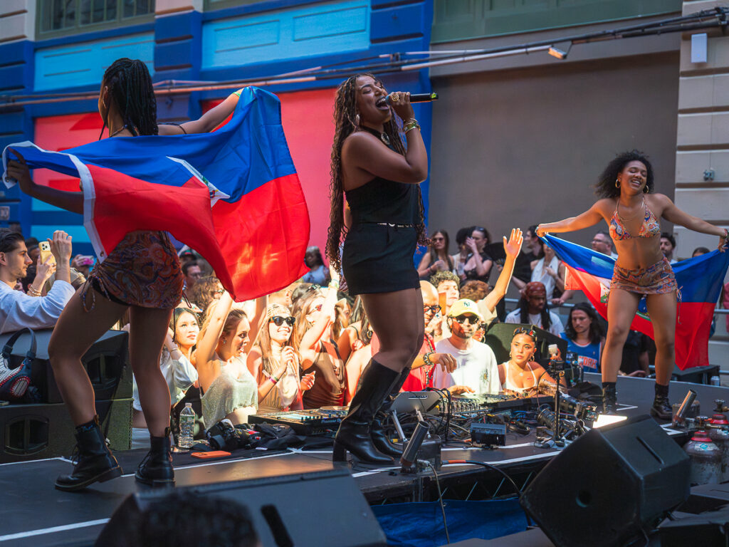 Rebecca Zama performing live with dancers waving the Haitian flag at Francis Mercier's Solèy in Industry City.