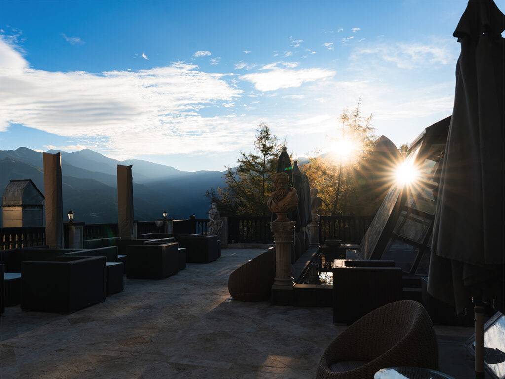 Rooftop terrace at Old England Manor with lounge seating and mountain views at sunrise in Qingjing, Taiwan.