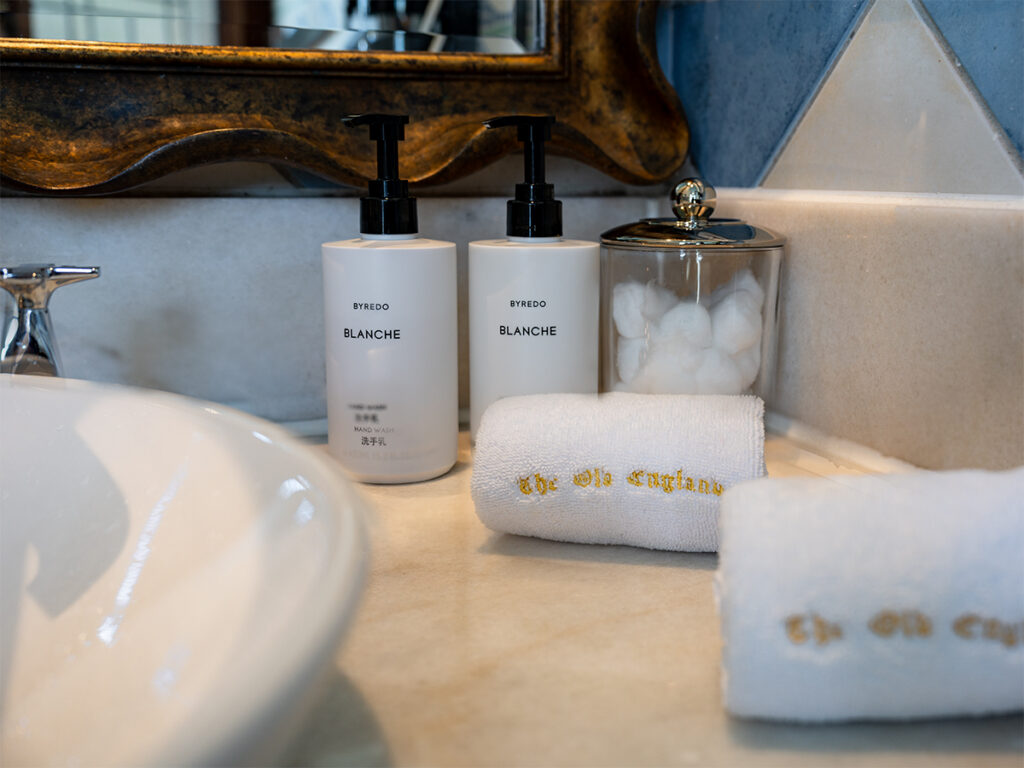 Byredo Blanche toiletries and embroidered towels on the bathroom counter at Old England Manor.