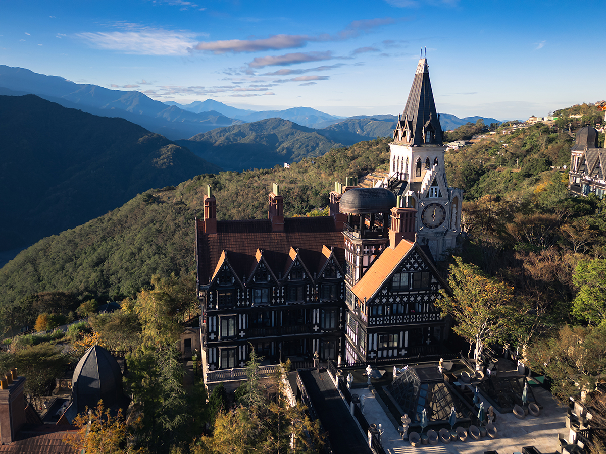 Aerial view of Old England Manor's Tudor-style architecture and Gothic clock tower in Qingjing, Taiwan.