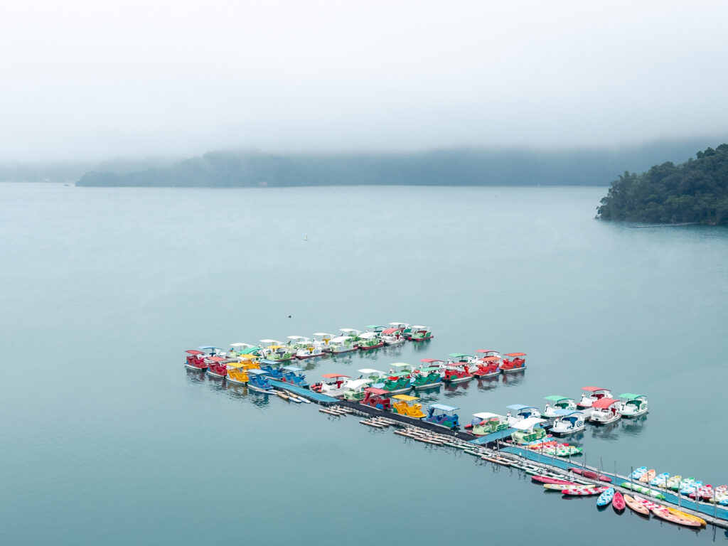 Colorful paddle boats docked on foggy Sun Moon Lake, the view from Hu Yue Lakeview Hotel on Day 1 of a 4 day Taiwan itinerary.