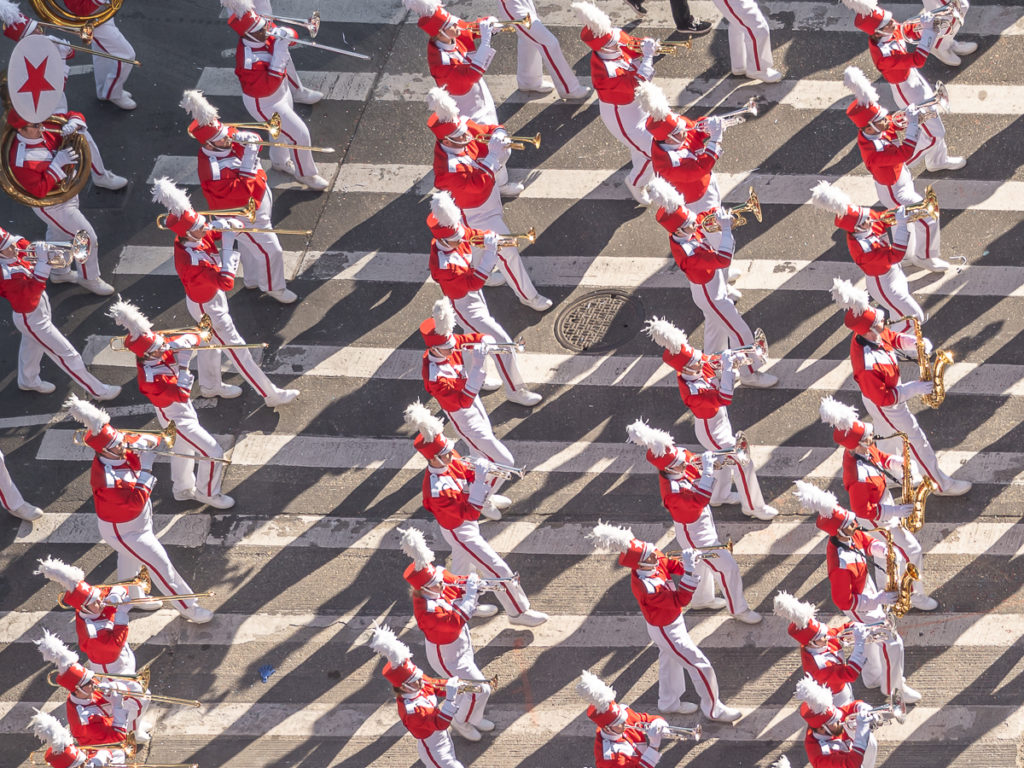 Close up red and white band members marching as seen from the Mandarin Oriental New York, the best hotel to watch the Thanksgiving Day Parade.