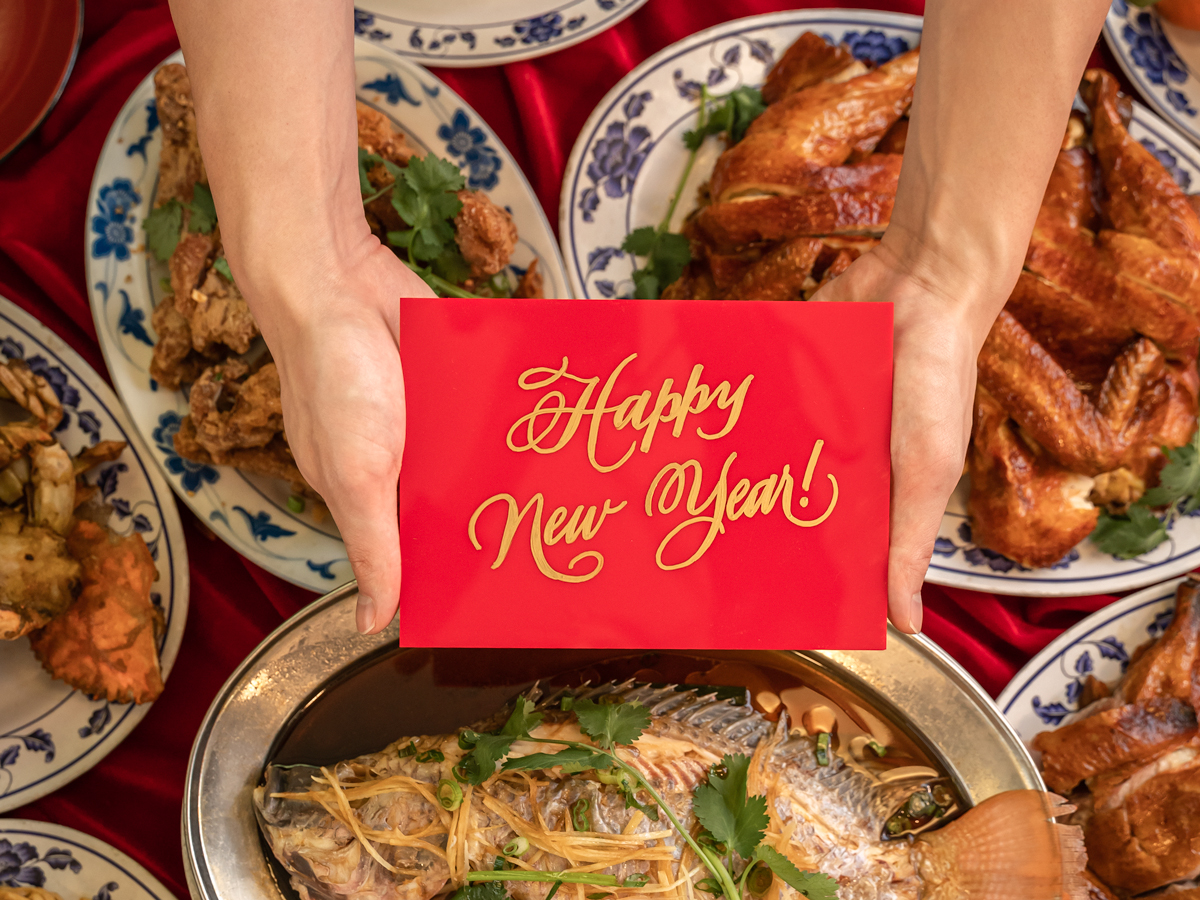Stop motion food photography of a happy new year sign over a full table of symbolic food.