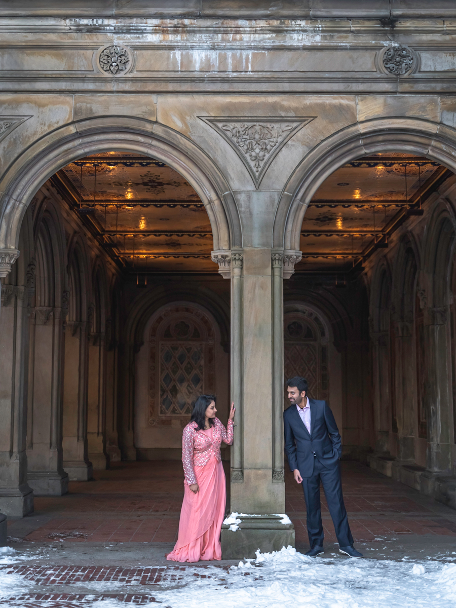 A couple looks at each other under the arches of Bethesda Terrace and Fountain in NYC.