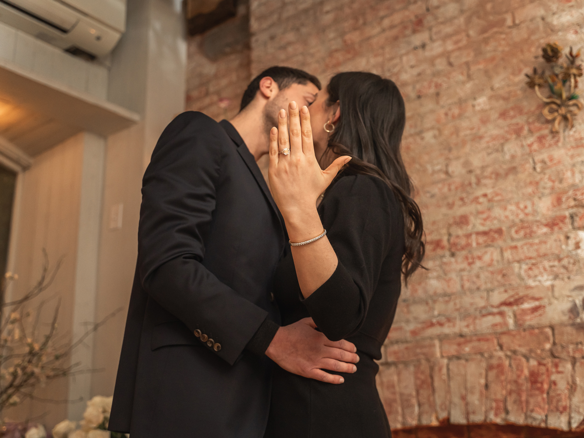 The newly engaged couple share a kiss and show off the engagement ring at Palma restaurant NYC.