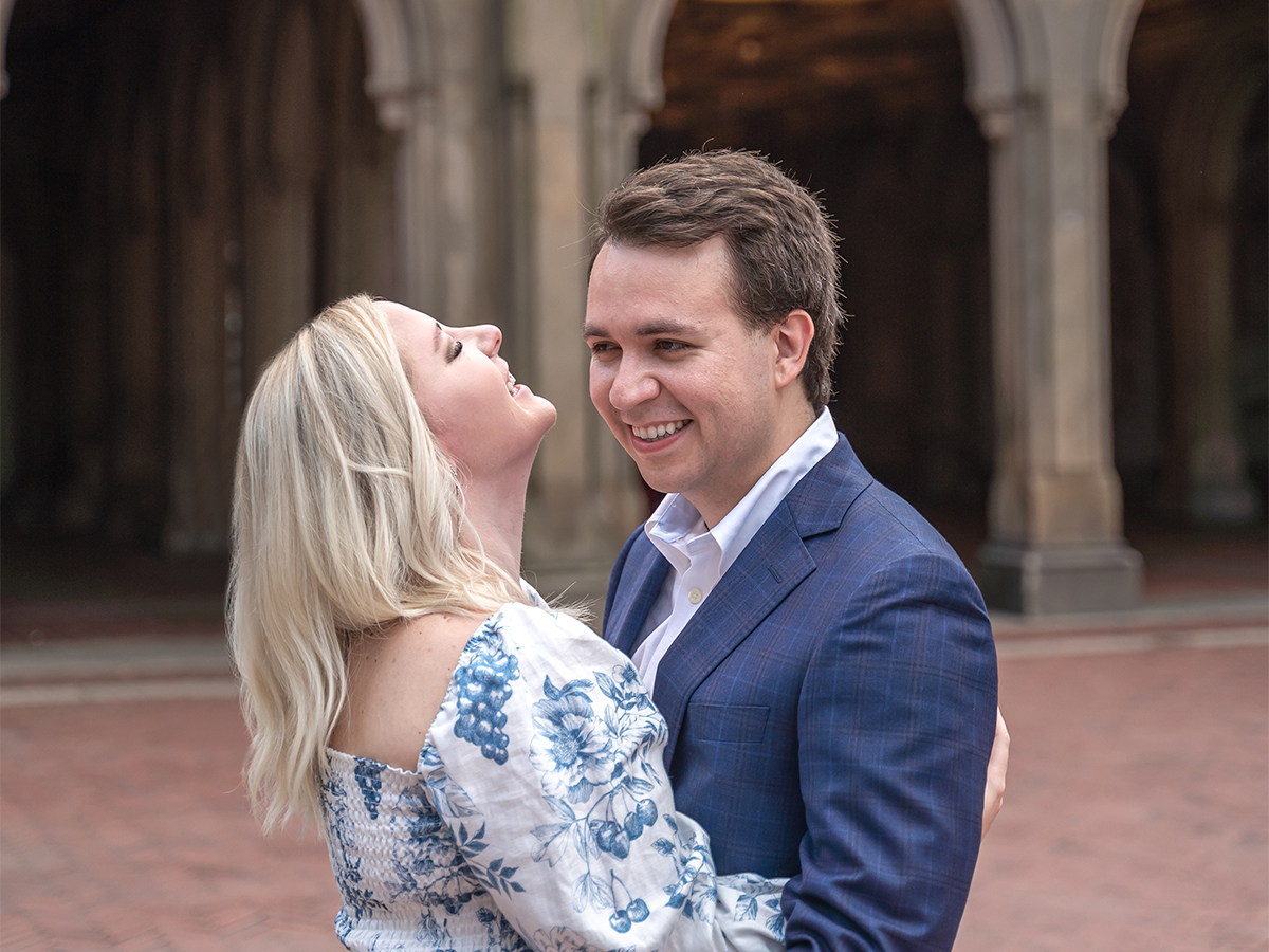 Neil Cato and Emily Hamilton pose happily together in front of the Bethesda Terrace after their central park proposal.