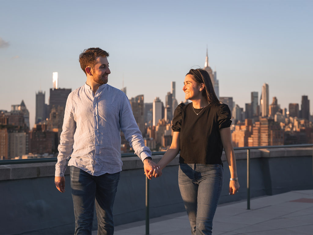Jordan Zauderer and his fiancé, Casey walk hand in hand during golden hour after their West Village rooftop engagement. 