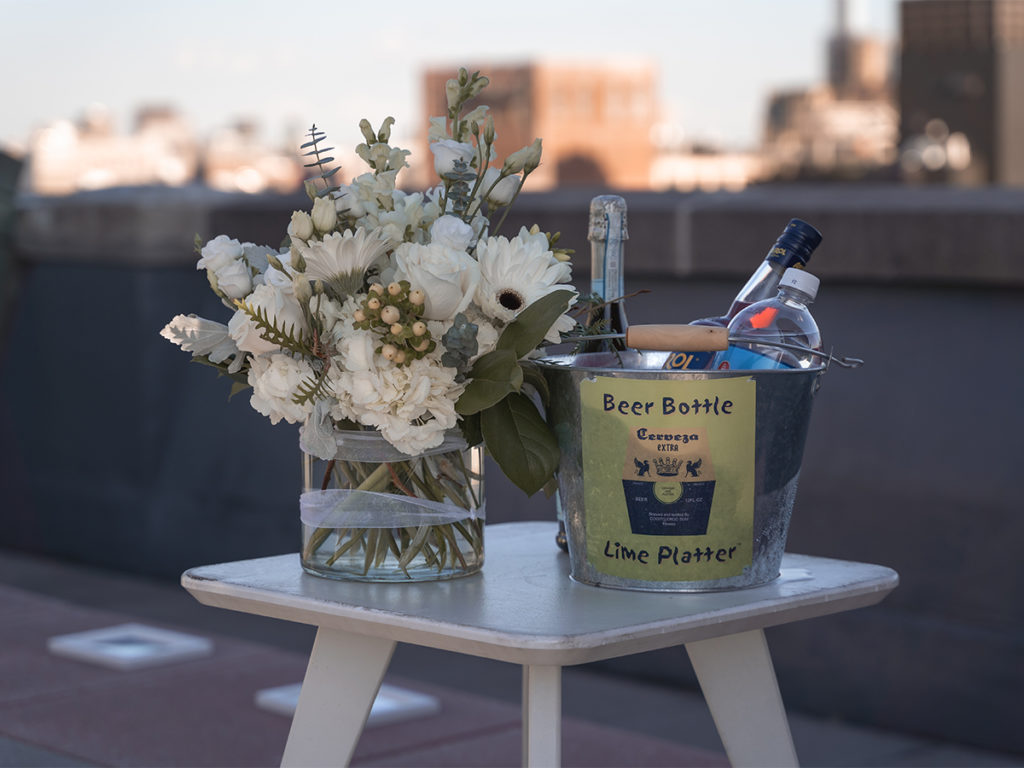 Details of the bouquet of flowers and a bucket of drinks to celebrate the West Village rooftop engagement.