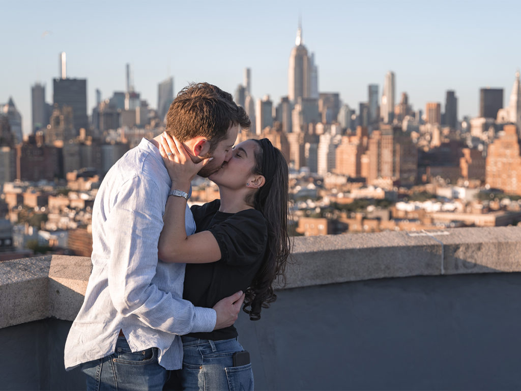 Jordan Zauderer and his fiancé, Casey embrace each other during golden hour after their West Village rooftop engagement and show of the diamond engagement ring.