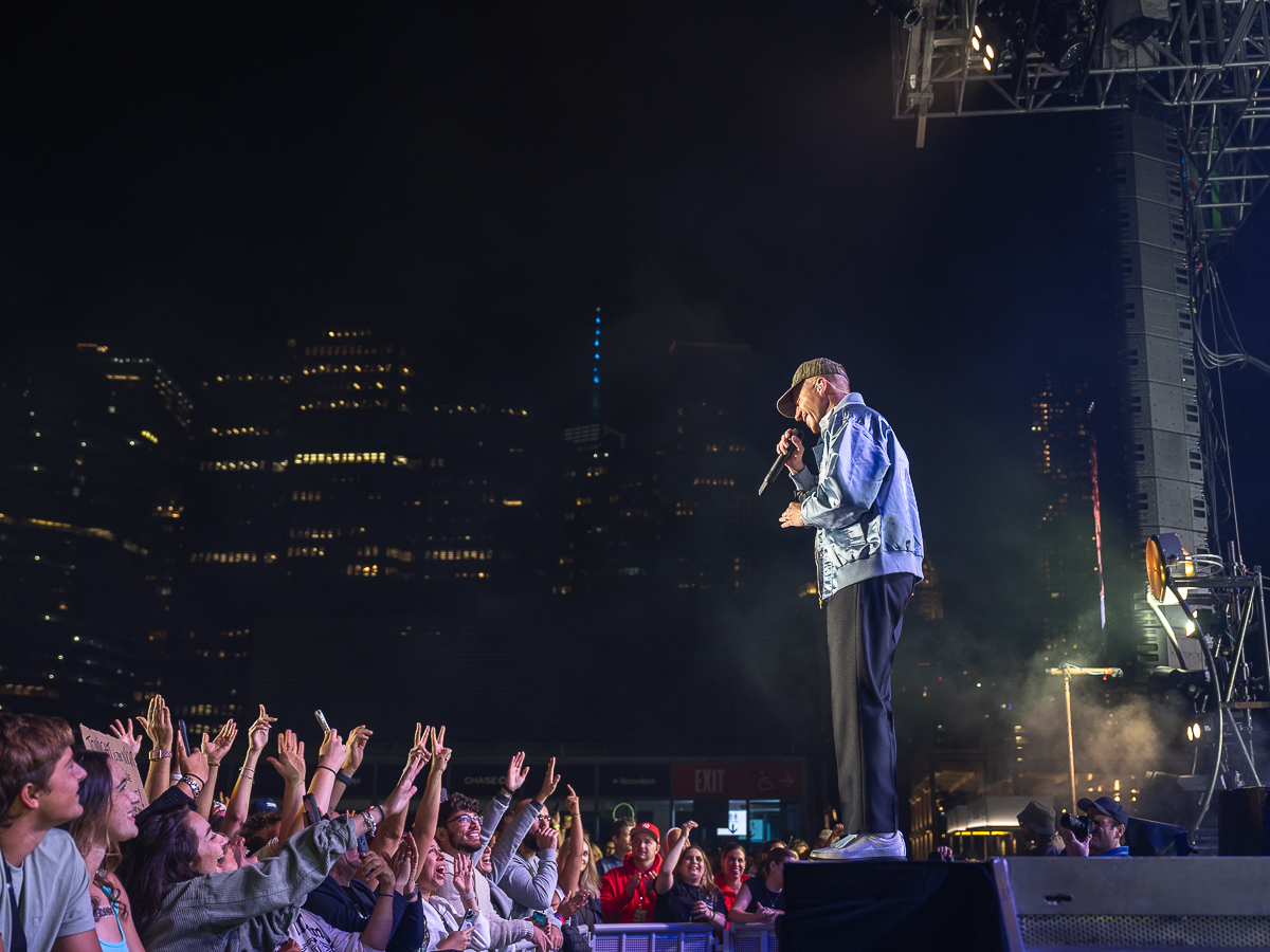 Rapper Macklemore talks to the audience at The Rooftop at Pier 17 with the World Trade Center in the background.