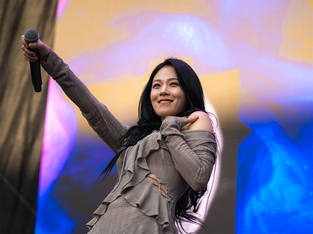 South Korean singer and rapper, BIBI, smiles and holds out her microphone at Head In The Clouds Festival.